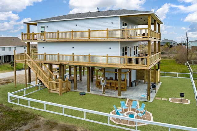 rear view of property featuring a yard, an outdoor fire pit, a wooden deck, and a patio