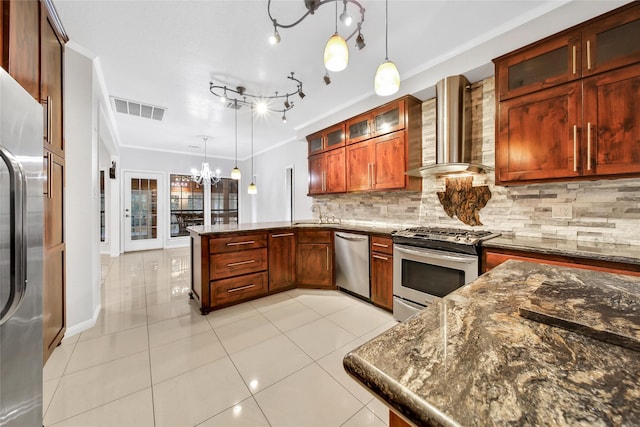 kitchen with decorative light fixtures, visible vents, wall chimney range hood, appliances with stainless steel finishes, and glass insert cabinets