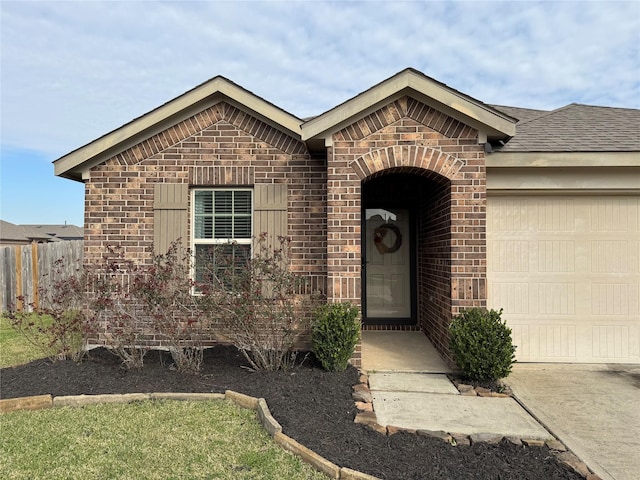 view of front of property featuring brick siding, an attached garage, and fence