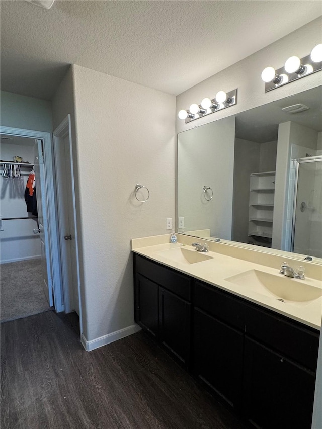 bathroom featuring a walk in closet, a sink, a textured ceiling, and wood finished floors