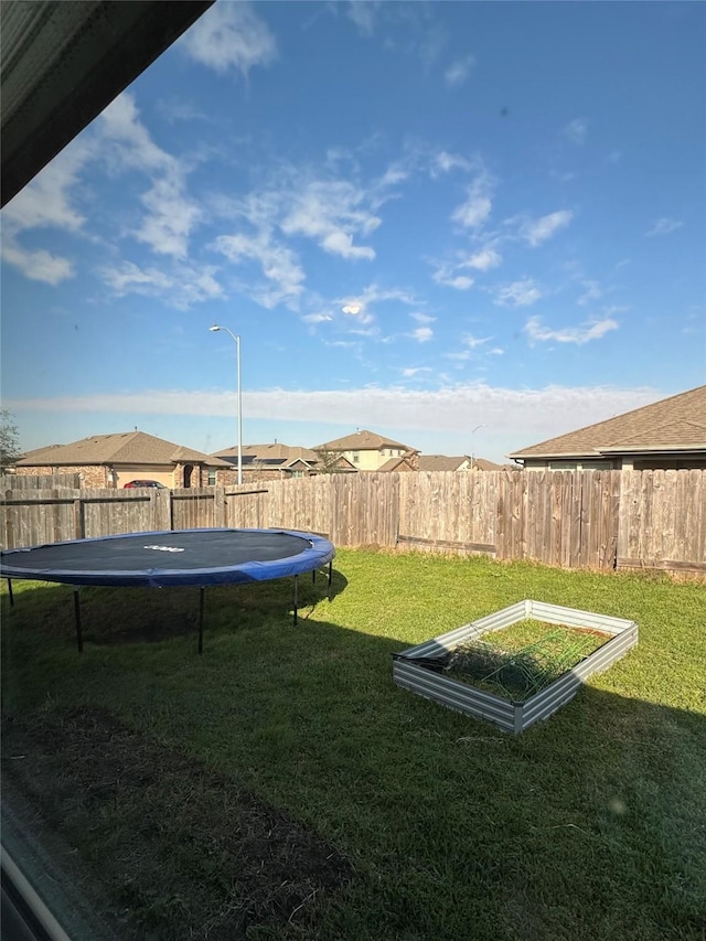 view of yard with a trampoline and a fenced backyard