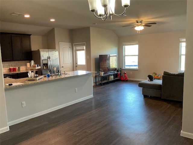 kitchen featuring tasteful backsplash, stainless steel fridge with ice dispenser, light stone counters, open floor plan, and dark wood-style flooring