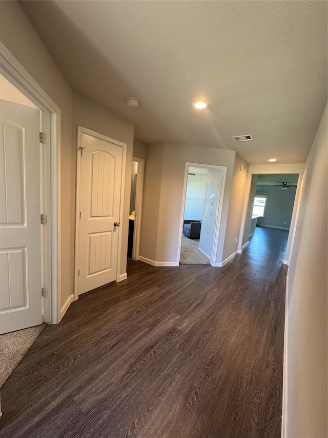 empty room featuring visible vents, baseboards, dark wood finished floors, ceiling fan, and a textured ceiling