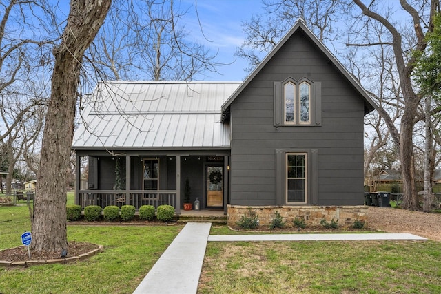 view of front of property featuring metal roof, stone siding, a porch, and a front yard