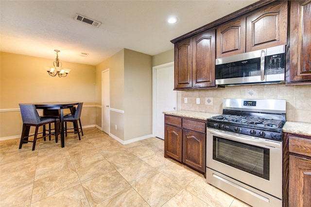 kitchen featuring appliances with stainless steel finishes, visible vents, dark brown cabinets, and light stone counters