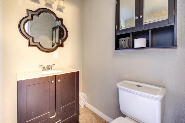 bathroom featuring toilet, tile patterned flooring, baseboards, and vanity