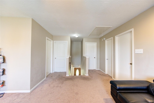 living room with attic access, baseboards, a textured ceiling, and light colored carpet