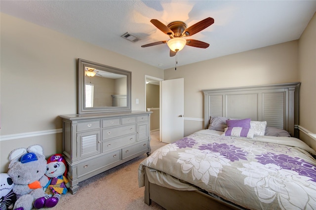 bedroom with light carpet, visible vents, and a ceiling fan