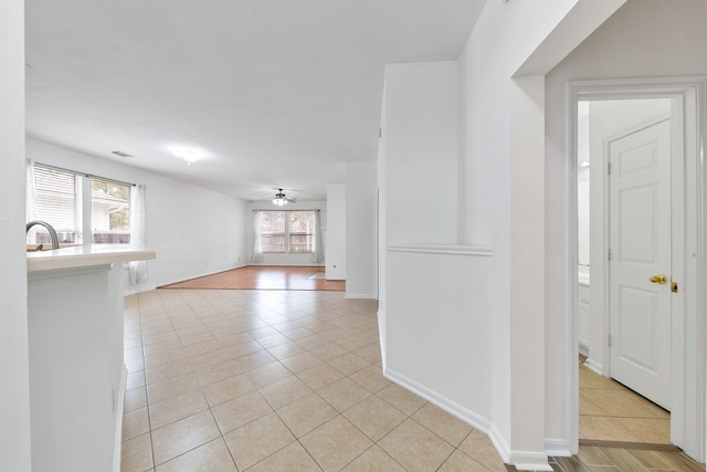 interior space with light tile patterned flooring, a ceiling fan, and baseboards