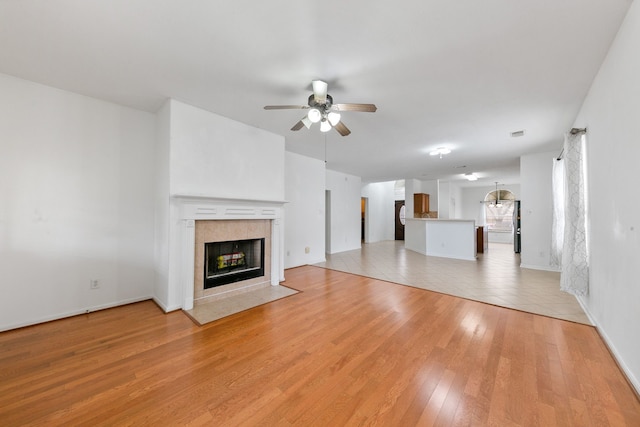 unfurnished living room featuring light wood-style floors, a fireplace, baseboards, and a ceiling fan