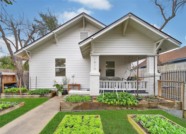 view of front of house featuring a porch, a vegetable garden, and fence