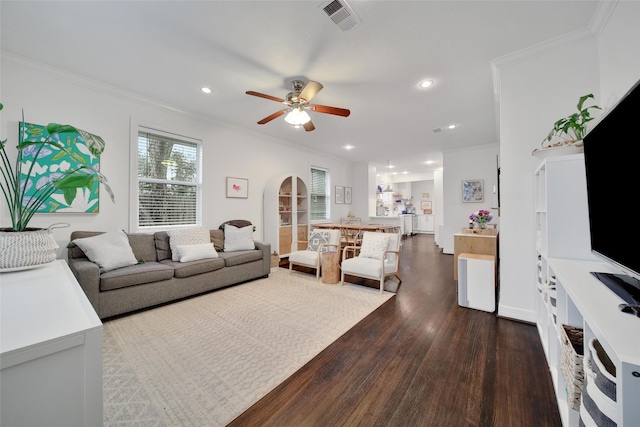 living room with arched walkways, dark wood finished floors, recessed lighting, visible vents, and ornamental molding