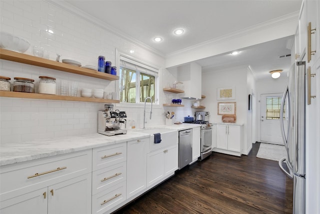 kitchen featuring white cabinets, light stone counters, stainless steel appliances, open shelves, and a sink