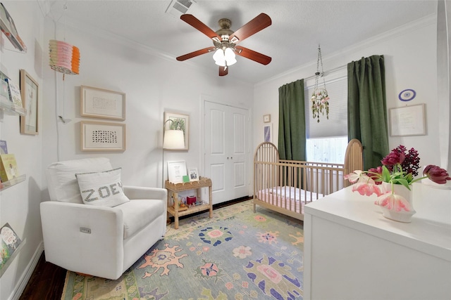 bedroom with visible vents, ceiling fan, wood finished floors, crown molding, and a closet