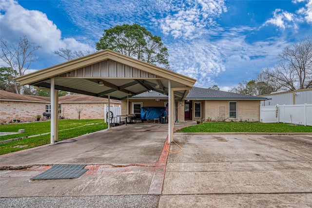 view of front of home featuring driveway, fence, a front yard, a carport, and brick siding