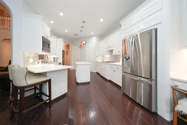 kitchen featuring white cabinets, a peninsula, appliances with stainless steel finishes, and arched walkways