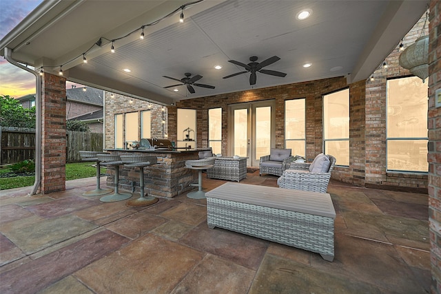 view of patio / terrace with fence, a ceiling fan, outdoor dry bar, french doors, and exterior kitchen