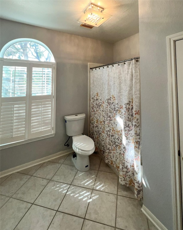 full bath featuring toilet, curtained shower, tile patterned flooring, and baseboards