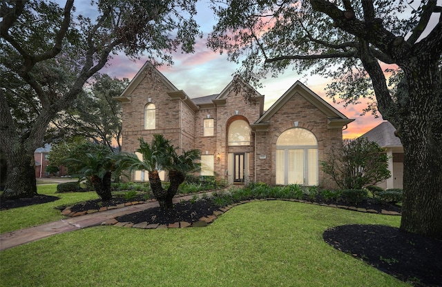 traditional-style house featuring a yard and brick siding