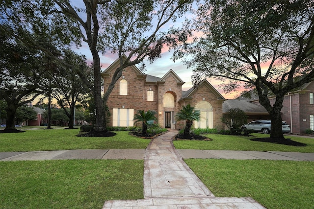 traditional-style home with brick siding and a front lawn