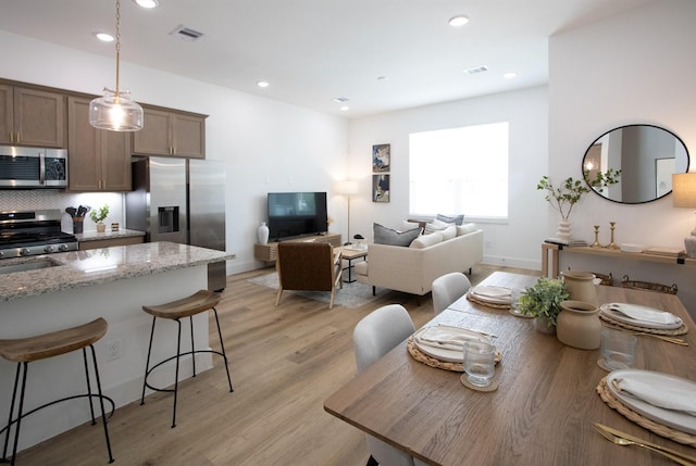 dining area featuring light wood-type flooring, baseboards, visible vents, and recessed lighting