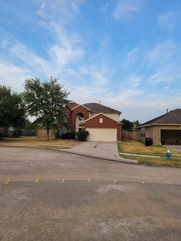 view of front of home with an attached garage, brick siding, fence, driveway, and a front yard