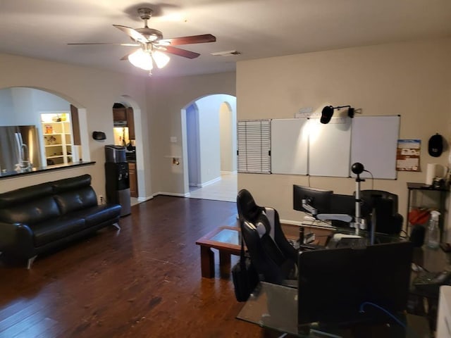 interior space featuring arched walkways, dark wood-type flooring, a ceiling fan, and baseboards