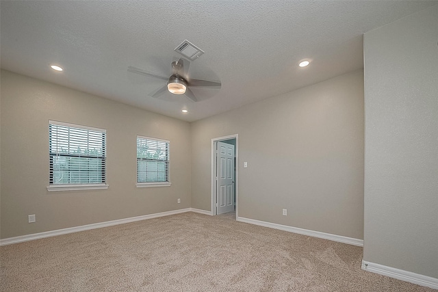 spare room with baseboards, visible vents, a textured ceiling, and light colored carpet