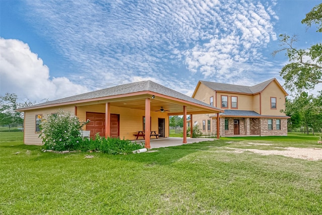 rear view of house with ceiling fan, a patio, a yard, and a carport