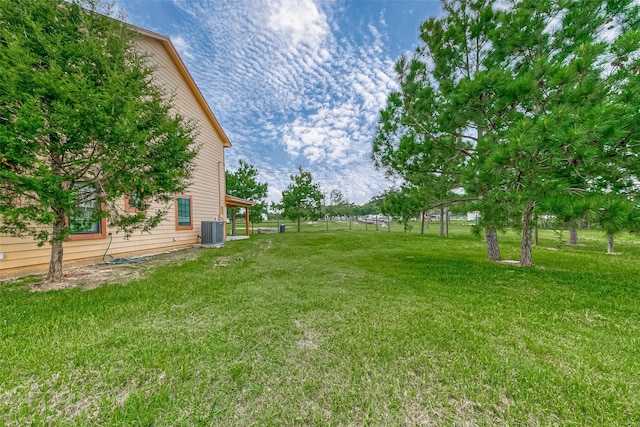 view of yard featuring central AC and fence