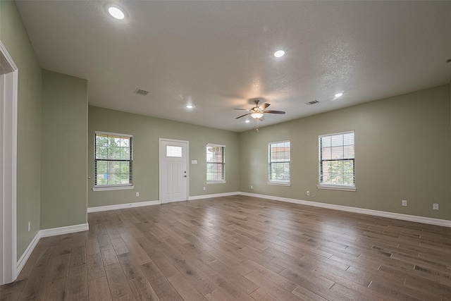 interior space featuring a ceiling fan, plenty of natural light, baseboards, and wood finished floors