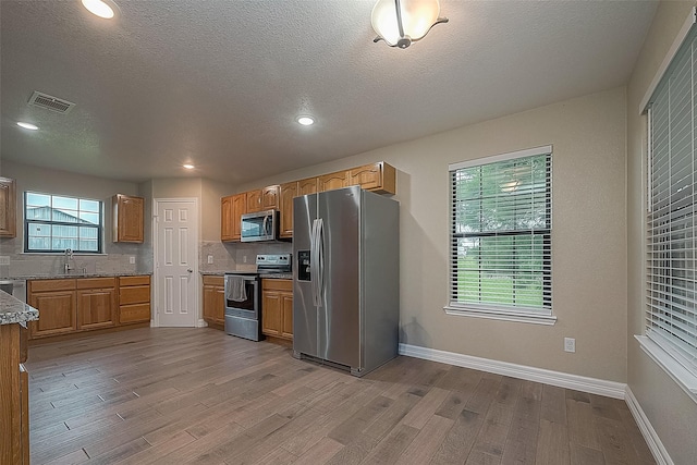 kitchen featuring visible vents, appliances with stainless steel finishes, tasteful backsplash, and light wood-style flooring