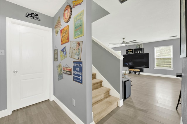 stairs featuring a ceiling fan, baseboards, and wood finished floors