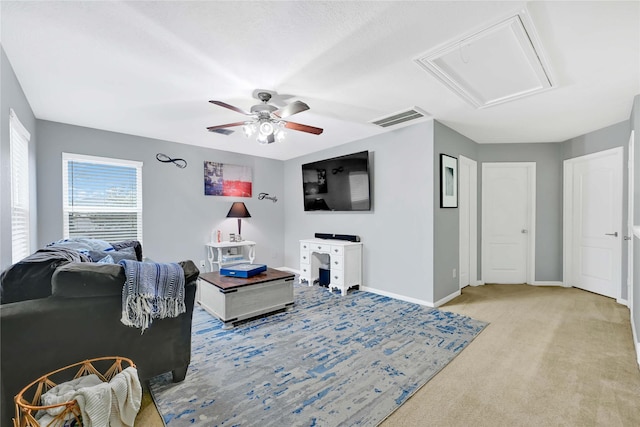 living area with baseboards, visible vents, a ceiling fan, and light colored carpet