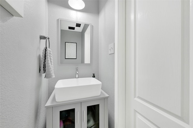 bathroom with a textured wall and vanity