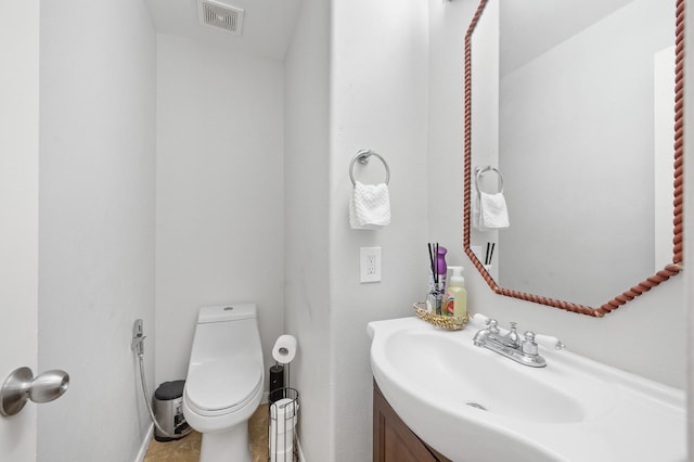 half bathroom featuring visible vents, vanity, and toilet