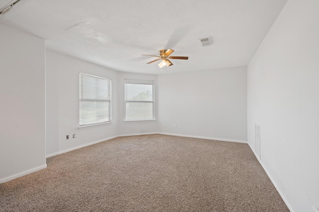 empty room with ceiling fan, carpet floors, visible vents, and baseboards