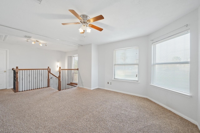 empty room featuring carpet floors, baseboards, visible vents, and a ceiling fan