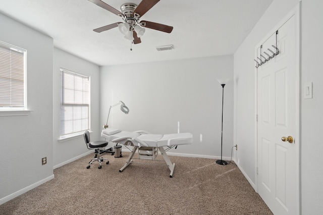 office space with light carpet, baseboards, visible vents, and ceiling fan