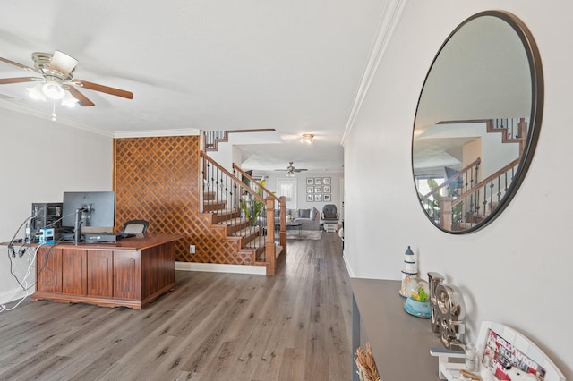 office area with crown molding, light wood finished floors, an accent wall, ceiling fan, and baseboards