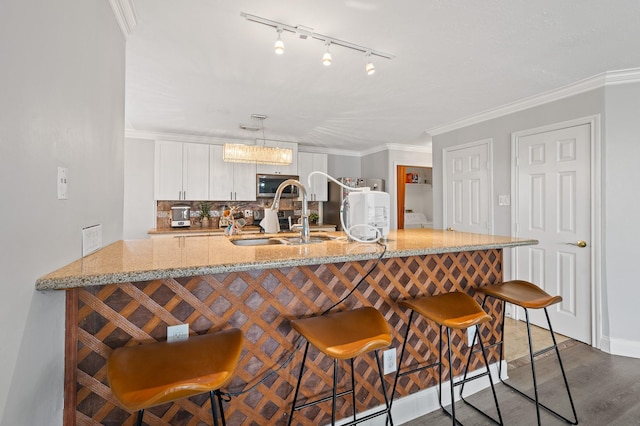 kitchen featuring a breakfast bar, a sink, decorative light fixtures, and white cabinets