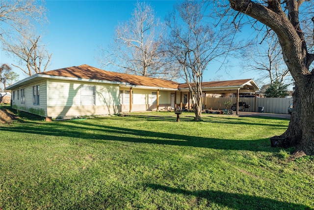 rear view of house featuring a yard and fence