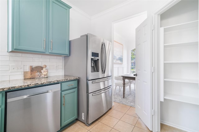 kitchen with stone counters, light tile patterned floors, backsplash, appliances with stainless steel finishes, and ornamental molding