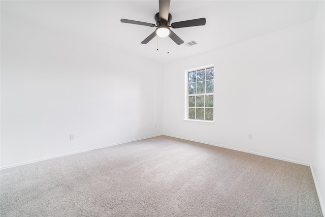 spare room with carpet floors, a ceiling fan, visible vents, and baseboards