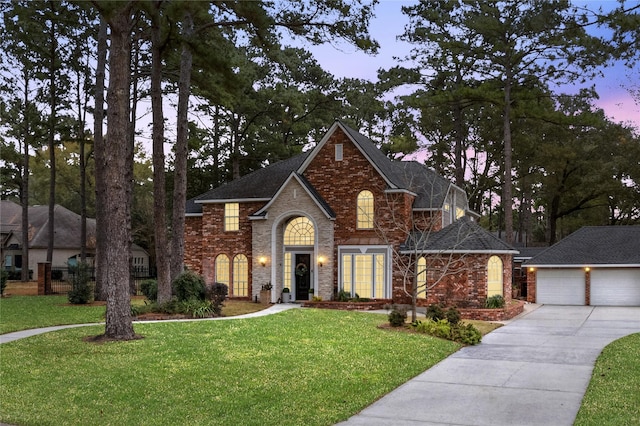 view of front facade with an outbuilding, a yard, brick siding, and concrete driveway