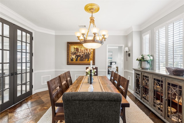 dining area with french doors, crown molding, stone tile floors, and an inviting chandelier