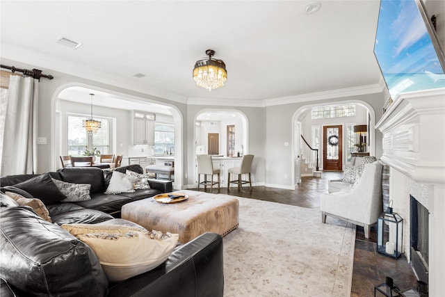 living room with arched walkways, a notable chandelier, a fireplace, visible vents, and ornamental molding