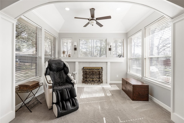 sunroom / solarium with a ceiling fan, arched walkways, and a tiled fireplace