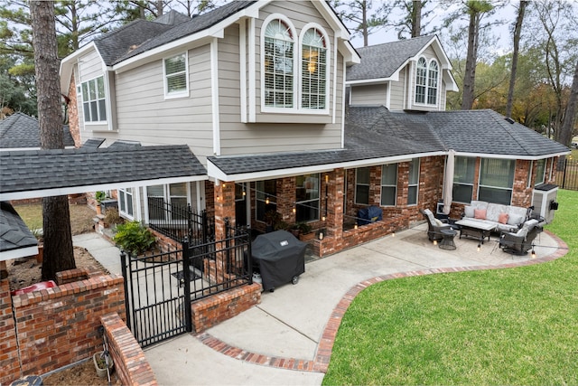 rear view of property with a patio area, a yard, an outdoor living space, and roof with shingles