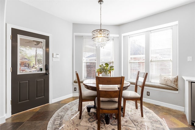 dining room featuring baseboards, a chandelier, and stone finish flooring